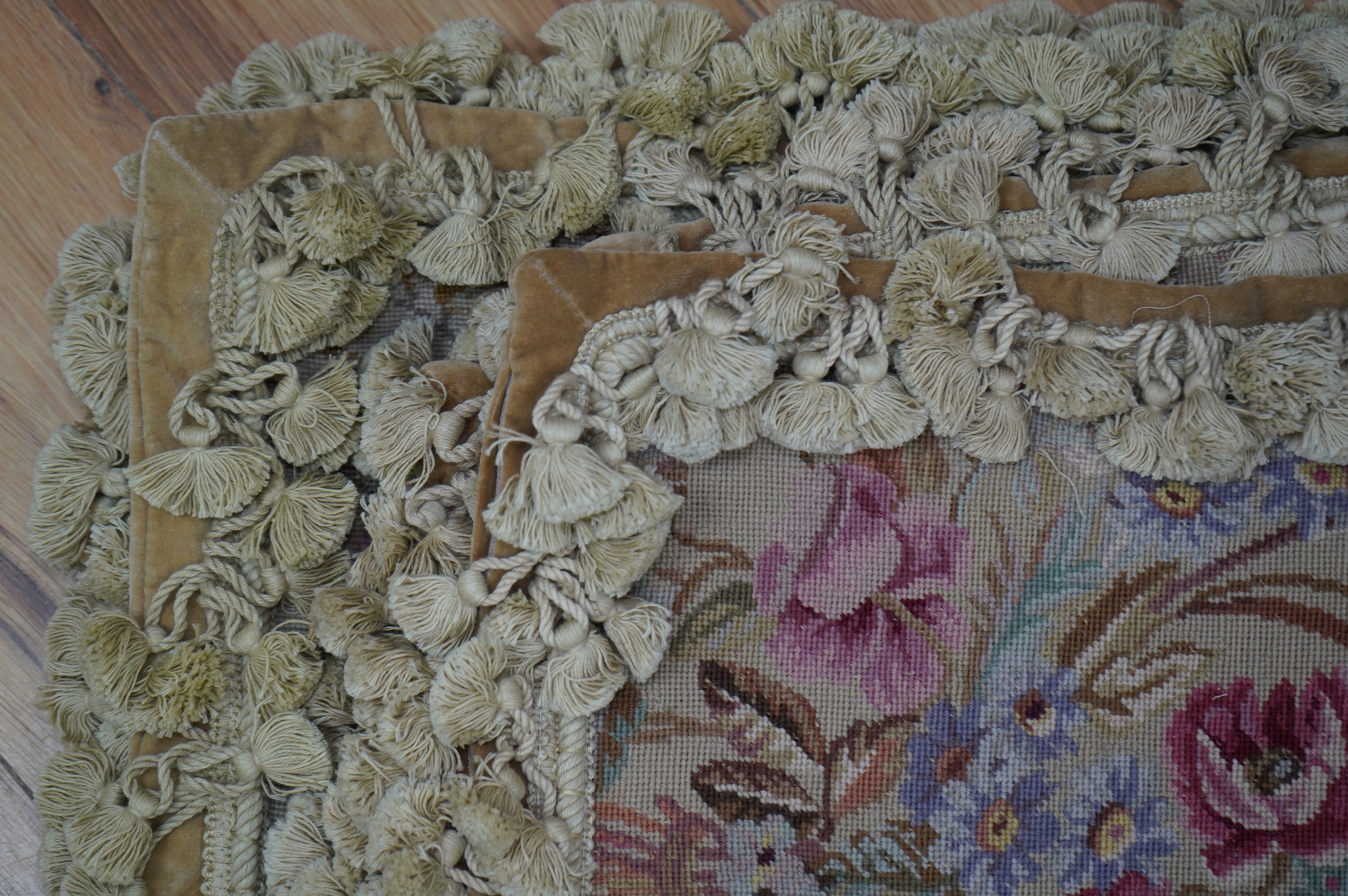 Four rectangular pink roses patterned wool worked cushions, all with mushroom tasselling, largest 46cm wide, 34cm high. Condition - good